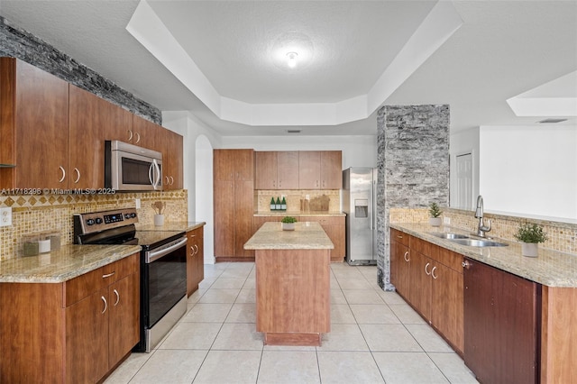 kitchen featuring tasteful backsplash, a raised ceiling, sink, light tile patterned floors, and stainless steel appliances