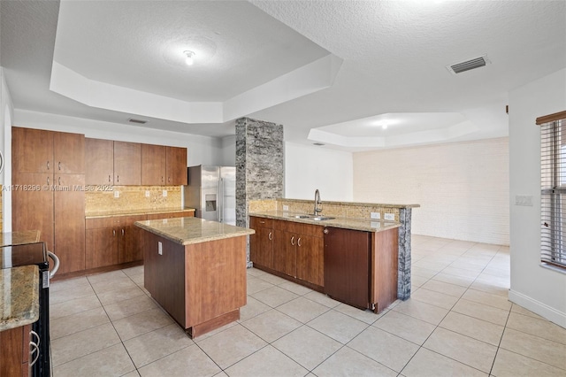 empty room with light tile patterned flooring, brick wall, and a tray ceiling