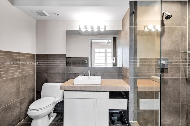 bathroom with tile walls, vanity, toilet, and an enclosed shower