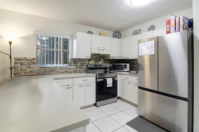 kitchen with light tile patterned floors, appliances with stainless steel finishes, white cabinetry, backsplash, and a textured ceiling