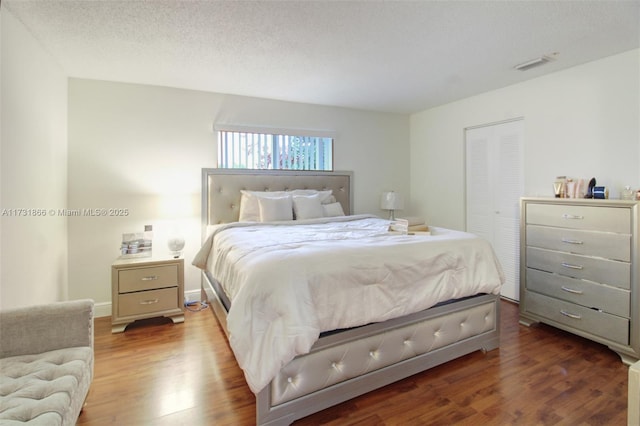 bedroom featuring dark hardwood / wood-style flooring, a closet, and a textured ceiling