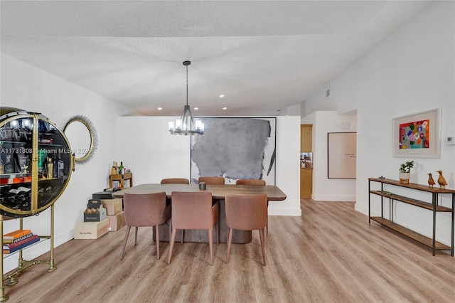 dining space featuring a textured ceiling, a chandelier, and light hardwood / wood-style floors