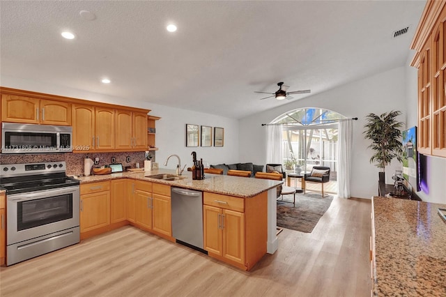 kitchen with sink, tasteful backsplash, kitchen peninsula, stainless steel appliances, and light hardwood / wood-style floors