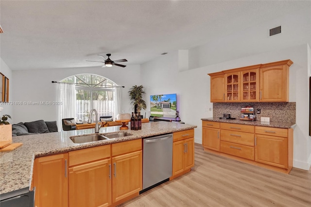 kitchen with tasteful backsplash, dishwasher, sink, light stone counters, and light wood-type flooring