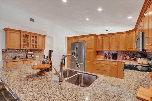 kitchen with sink, stainless steel appliances, light stone counters, a kitchen bar, and vaulted ceiling