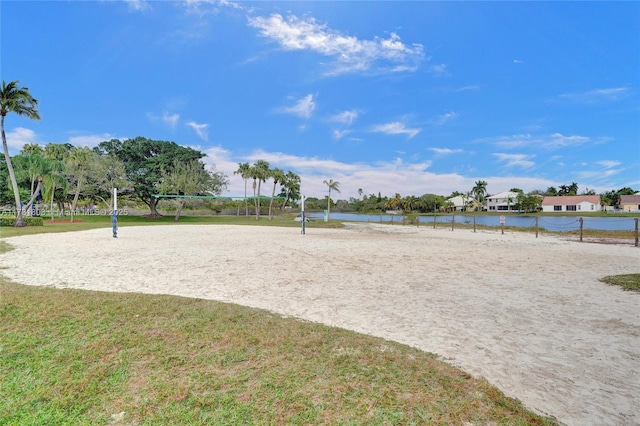 view of home's community with a lawn, volleyball court, and a water view