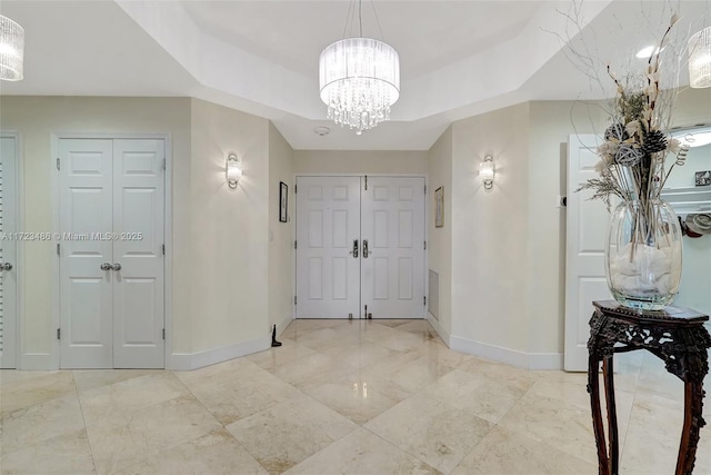 entrance foyer featuring a raised ceiling and a notable chandelier