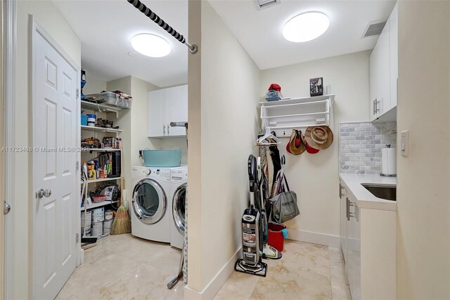 clothes washing area featuring independent washer and dryer and cabinets