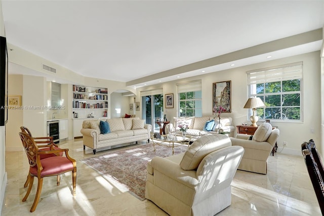 living room with wine cooler, a wealth of natural light, and built in features