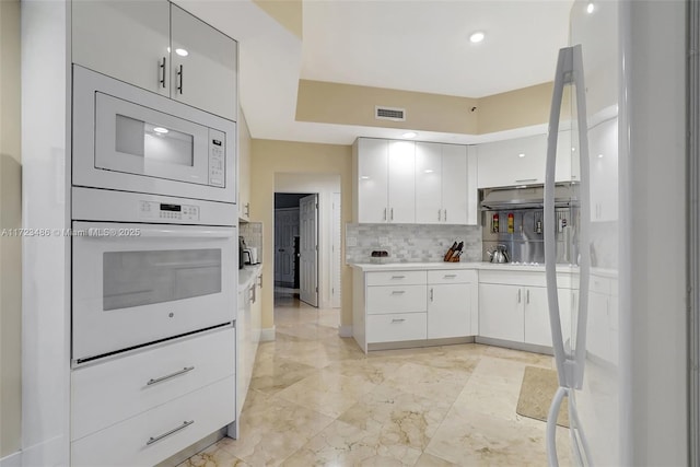 kitchen featuring white cabinetry, white appliances, and tasteful backsplash