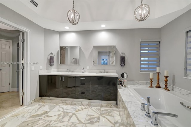 bathroom featuring vanity, a relaxing tiled tub, and a notable chandelier