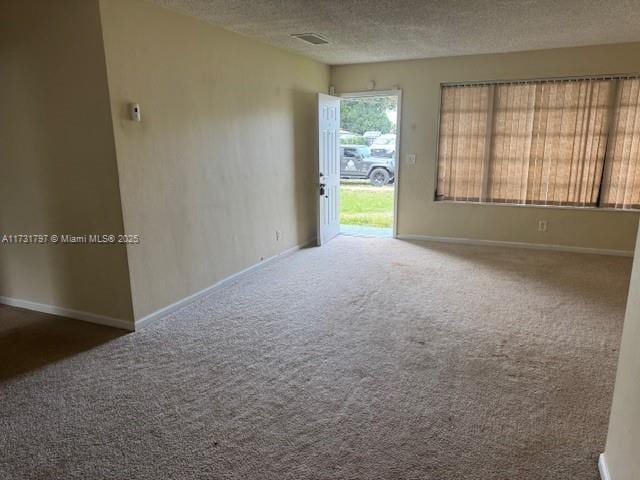 carpeted empty room with a textured ceiling