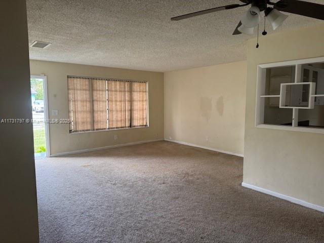 unfurnished room featuring ceiling fan, carpet, a textured ceiling, and built in shelves