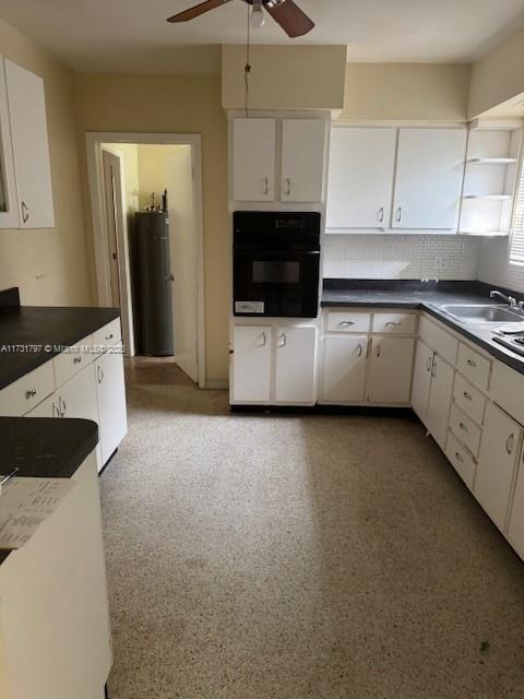 kitchen featuring white cabinetry, sink, water heater, and oven