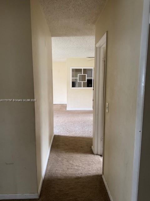 hallway featuring carpet flooring and a textured ceiling