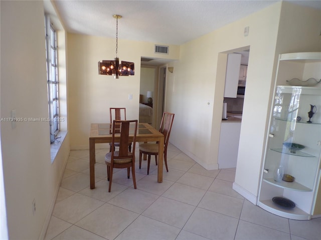 tiled dining room with a chandelier