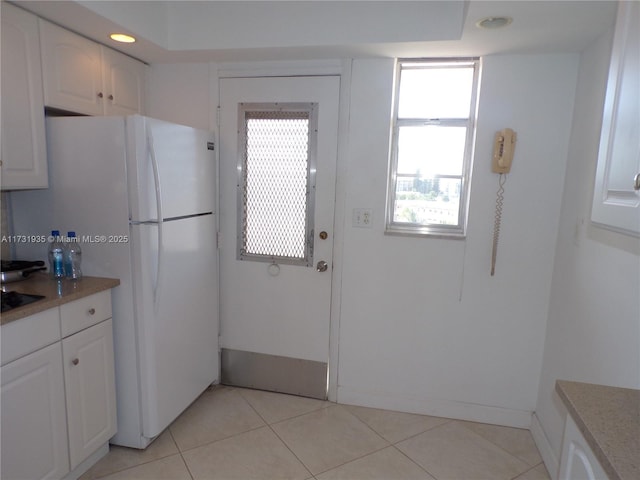 kitchen featuring white fridge, white cabinets, and light tile patterned flooring