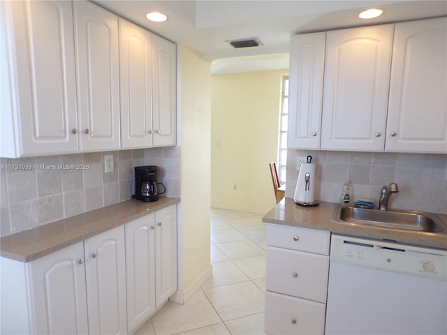 kitchen featuring sink, white cabinets, decorative backsplash, light tile patterned floors, and white dishwasher