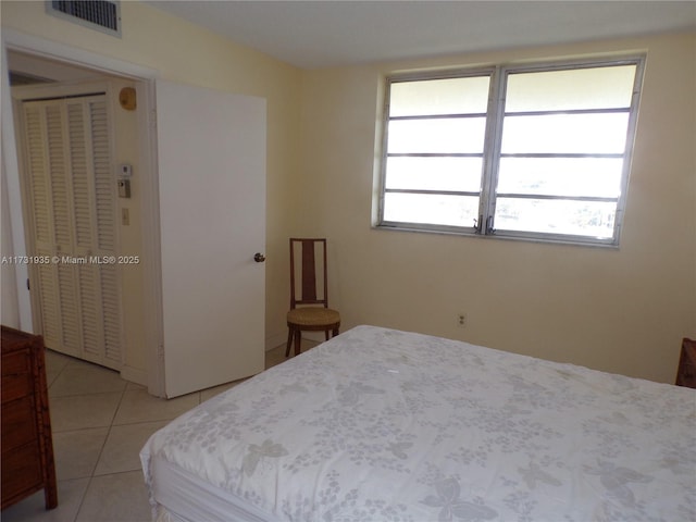 bedroom with multiple windows, light tile patterned floors, and a closet