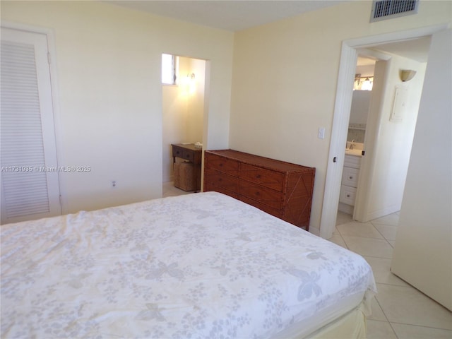 bedroom with connected bathroom and light tile patterned floors