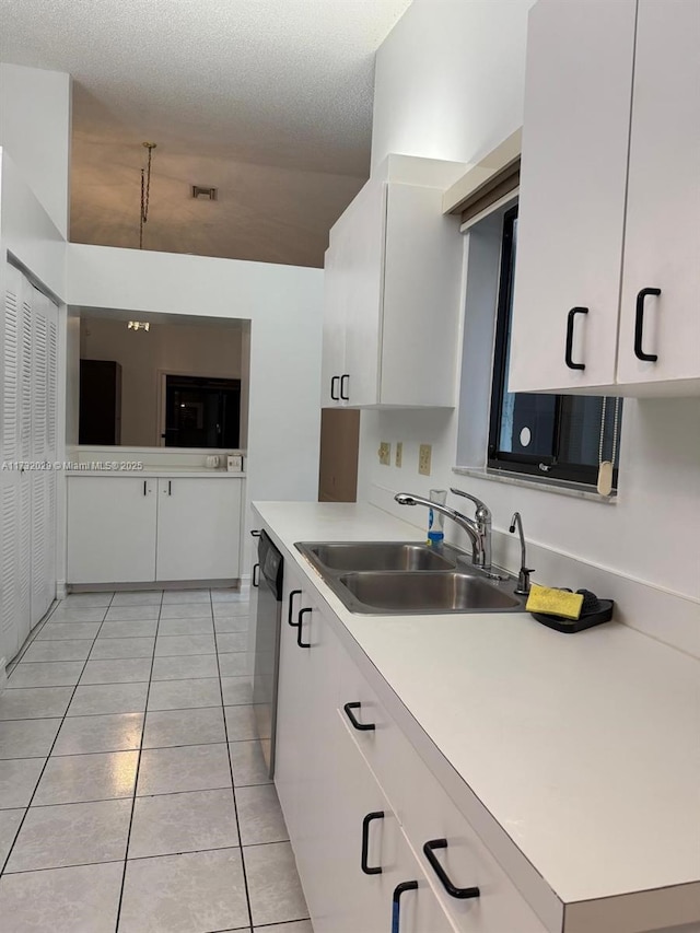 kitchen with sink, light tile patterned flooring, a textured ceiling, white cabinets, and stainless steel dishwasher