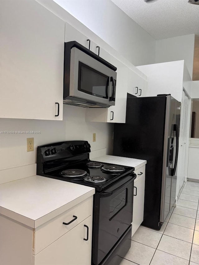 kitchen featuring stainless steel appliances, white cabinetry, light tile patterned floors, and a textured ceiling