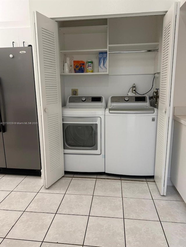 laundry area featuring laundry area, light tile patterned floors, and washing machine and clothes dryer