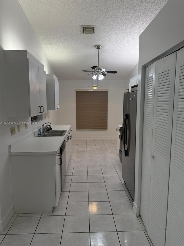 kitchen with sink, black fridge, a textured ceiling, light tile patterned floors, and ceiling fan