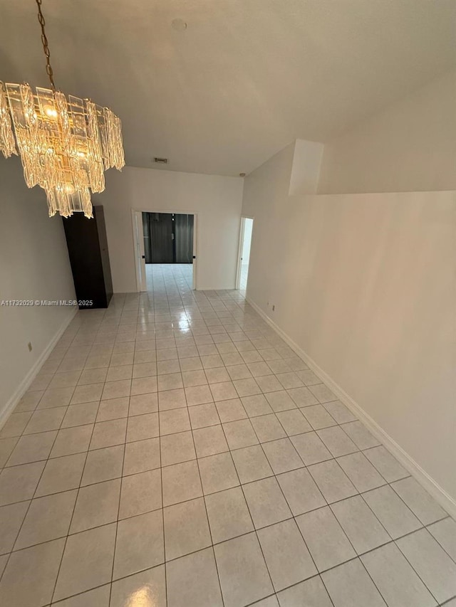 unfurnished room featuring baseboards, a chandelier, and light tile patterned flooring