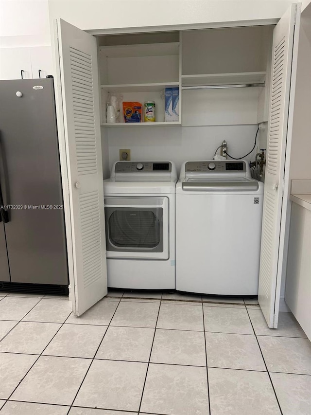 clothes washing area featuring light tile patterned flooring and washer and clothes dryer