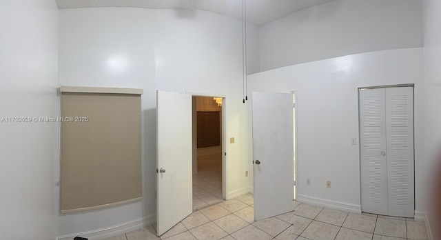 bathroom with high vaulted ceiling, a closet, and tile patterned floors