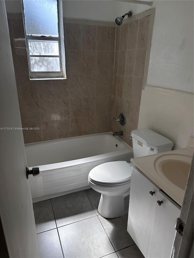 full bathroom featuring tile patterned floors, toilet, tiled shower / bath, tile walls, and vanity