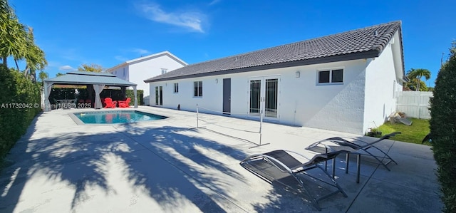 rear view of property featuring a fenced in pool, a gazebo, and a patio