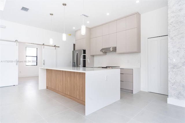 kitchen with light tile patterned flooring, stainless steel refrigerator with ice dispenser, an island with sink, pendant lighting, and a barn door