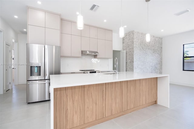 kitchen featuring pendant lighting, an island with sink, stainless steel fridge with ice dispenser, and decorative backsplash