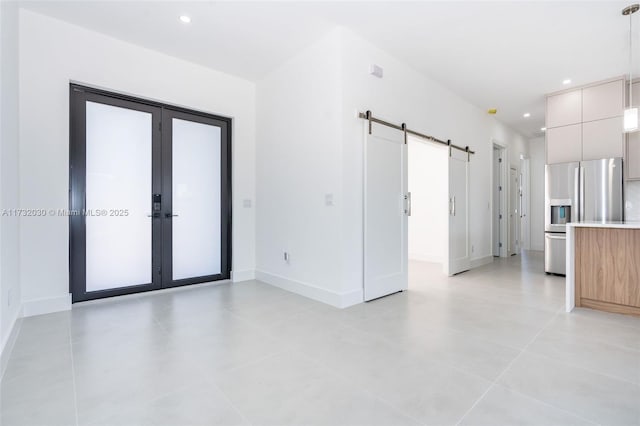 interior space featuring a barn door, light tile patterned floors, and french doors