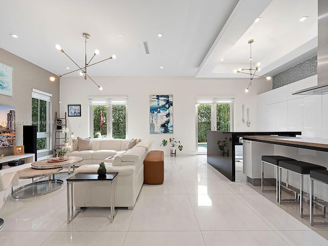 tiled living room featuring a tray ceiling and a chandelier