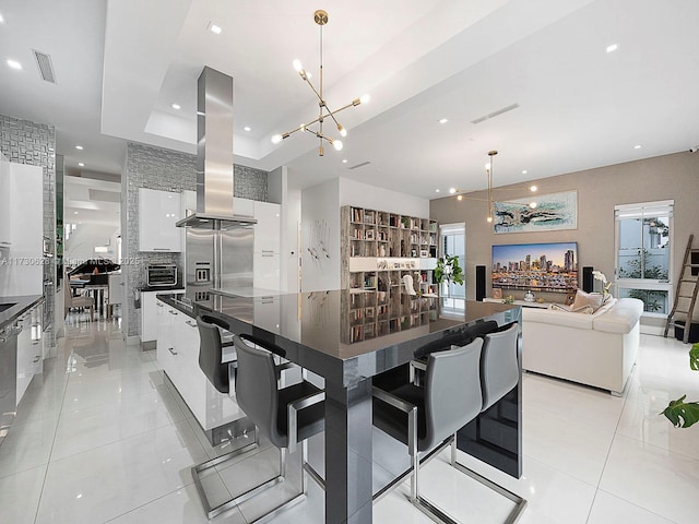 kitchen featuring pendant lighting, white cabinetry, island exhaust hood, light tile patterned floors, and a spacious island