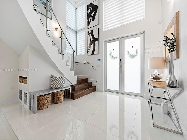 tiled foyer entrance with a towering ceiling and french doors