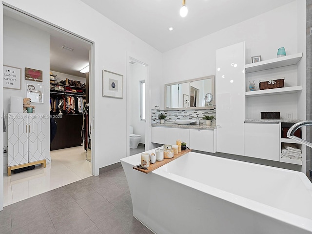 bathroom with tile patterned flooring, a bathing tub, vanity, and toilet