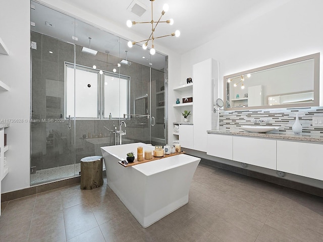 bathroom featuring an inviting chandelier, vanity, plus walk in shower, decorative backsplash, and tile patterned floors