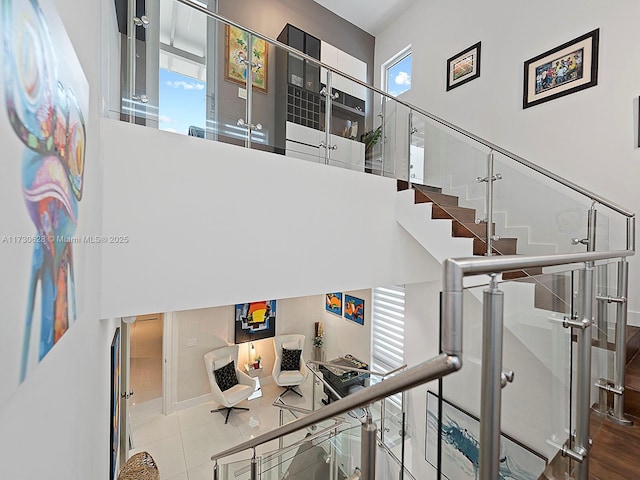 stairway with tile patterned flooring, a high ceiling, and a wealth of natural light