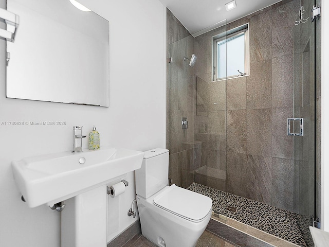 bathroom featuring a shower with shower door and toilet