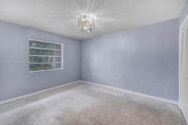 spare room featuring a notable chandelier and a textured ceiling