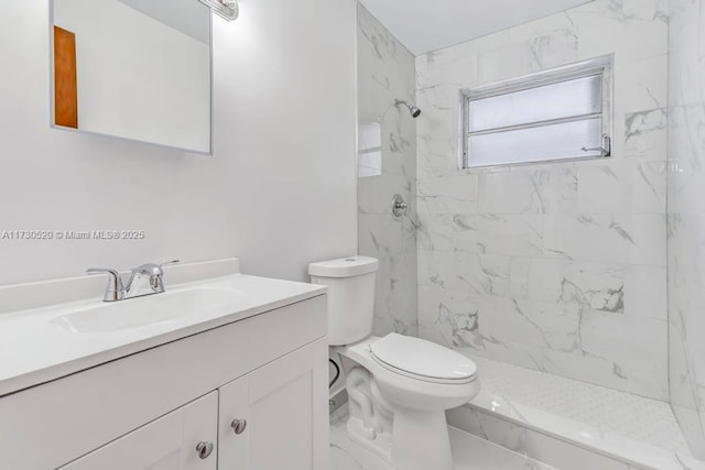 bathroom featuring vanity, a tile shower, and toilet