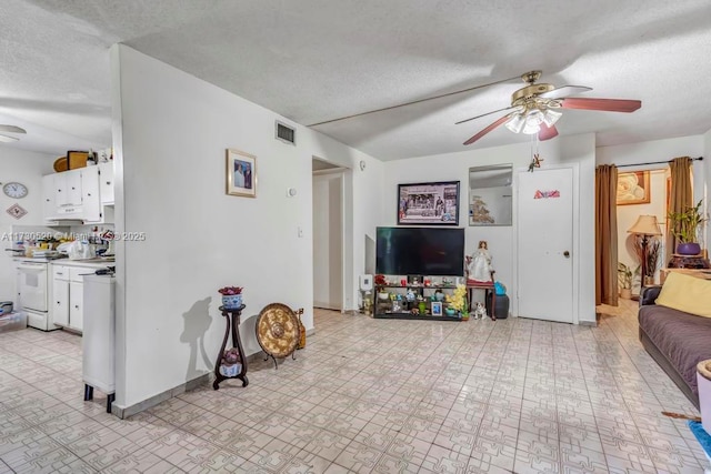 living room featuring ceiling fan and a textured ceiling