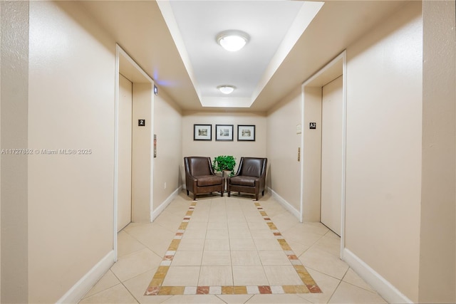 corridor with light tile patterned floors, a raised ceiling, and elevator