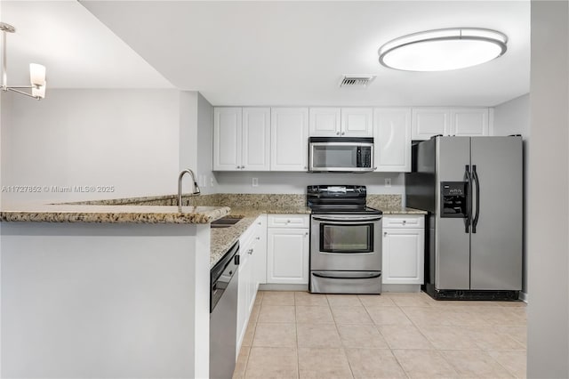 kitchen featuring light tile patterned floors, stainless steel appliances, light stone countertops, white cabinets, and kitchen peninsula