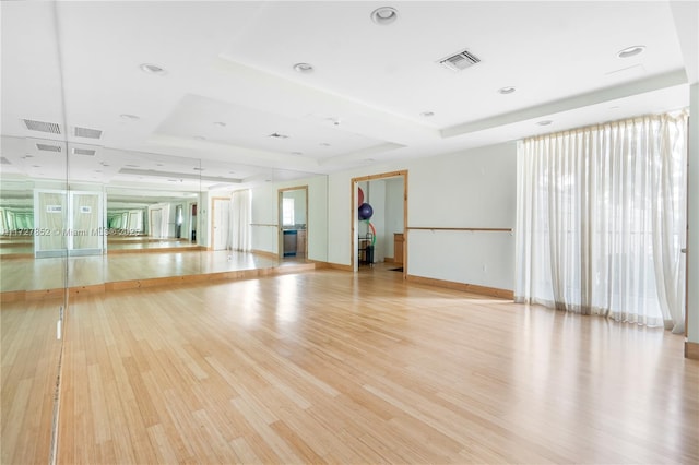 empty room featuring a tray ceiling and light hardwood / wood-style flooring