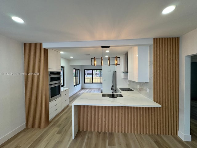 kitchen featuring sink, white cabinetry, hanging light fixtures, black electric cooktop, and kitchen peninsula